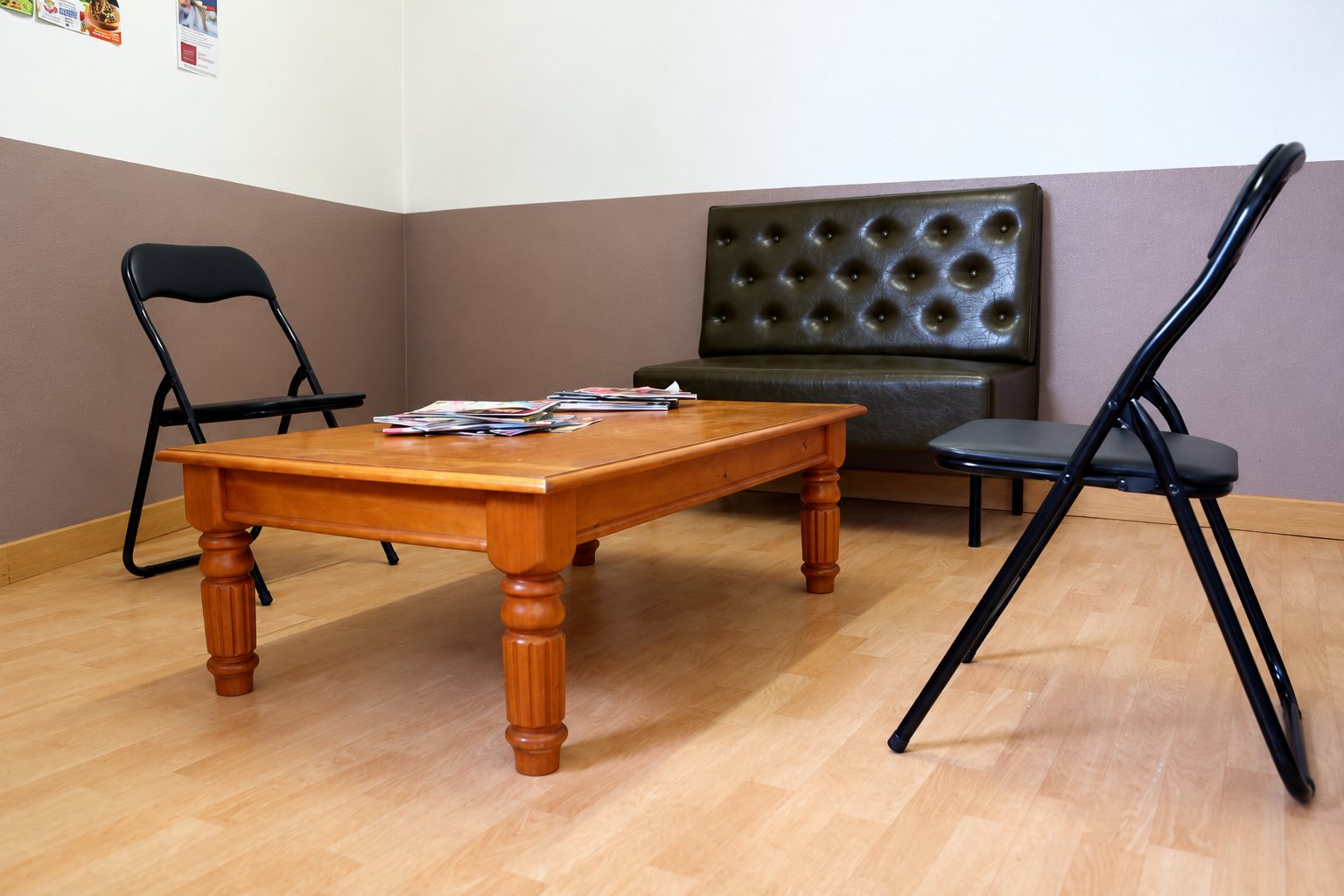 Salle d'attente : banquette capitonnée, table basse en bois et chaises pliantes