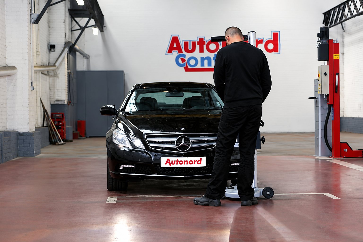Technicien contrôlant les phares d'une Mercedes noire dans l'atelier du centre